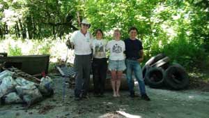 four people in front of pile of trash